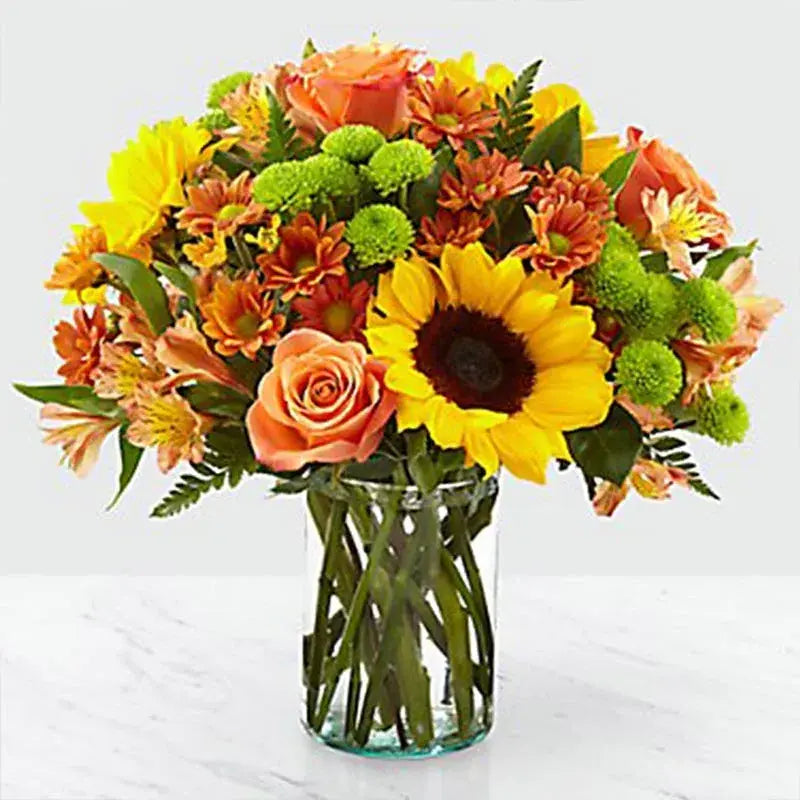 Vibrant Blooms, Stunning Floral Arrangement, Orange Roses, Sunflowers, Chrysanthemums, Alstroemeria, Green Button Chrysanthemums, Leather Fern Leaves, Glass Vase